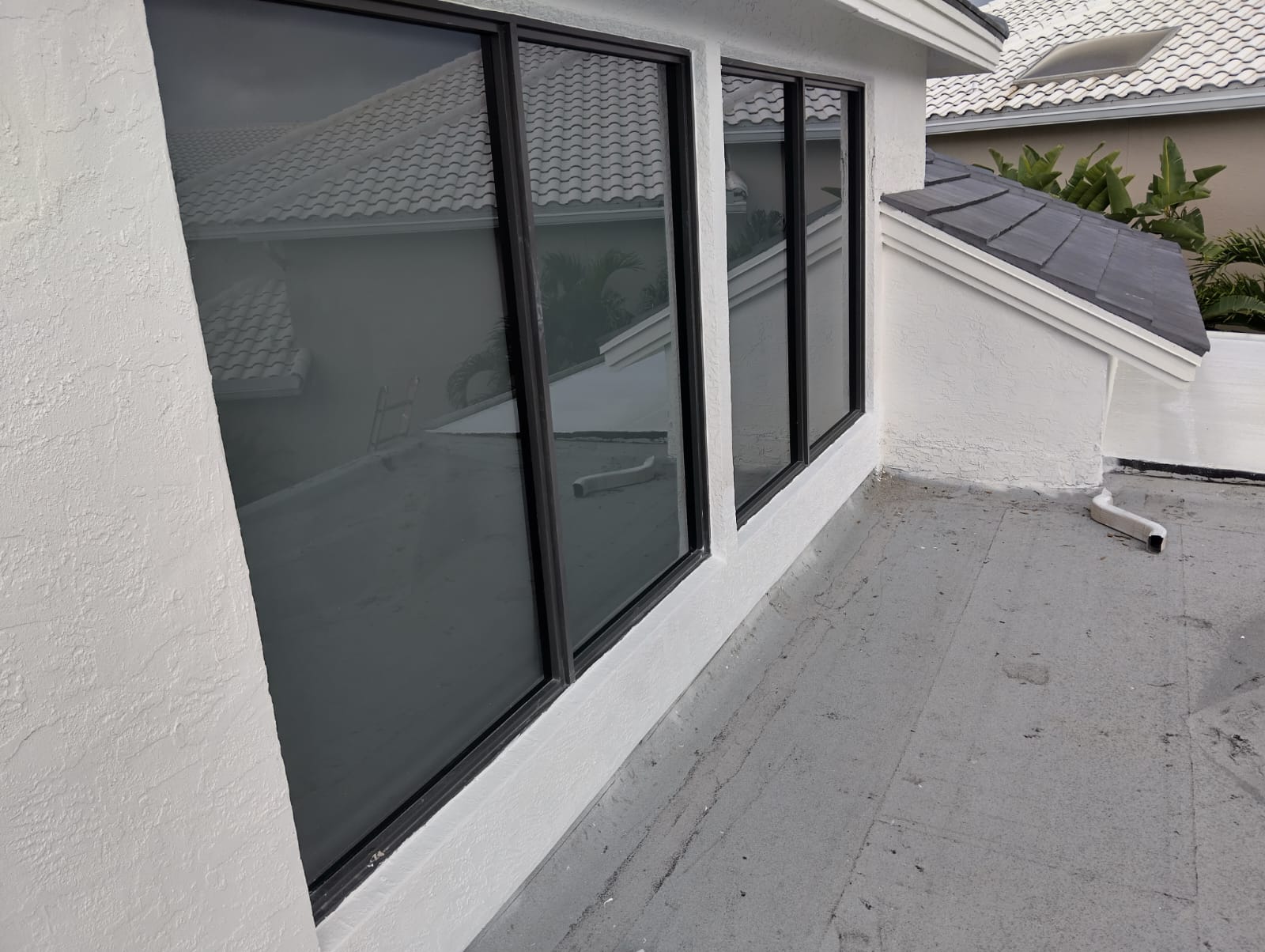 Finished impact windows beside a completed roofline and wall transition.